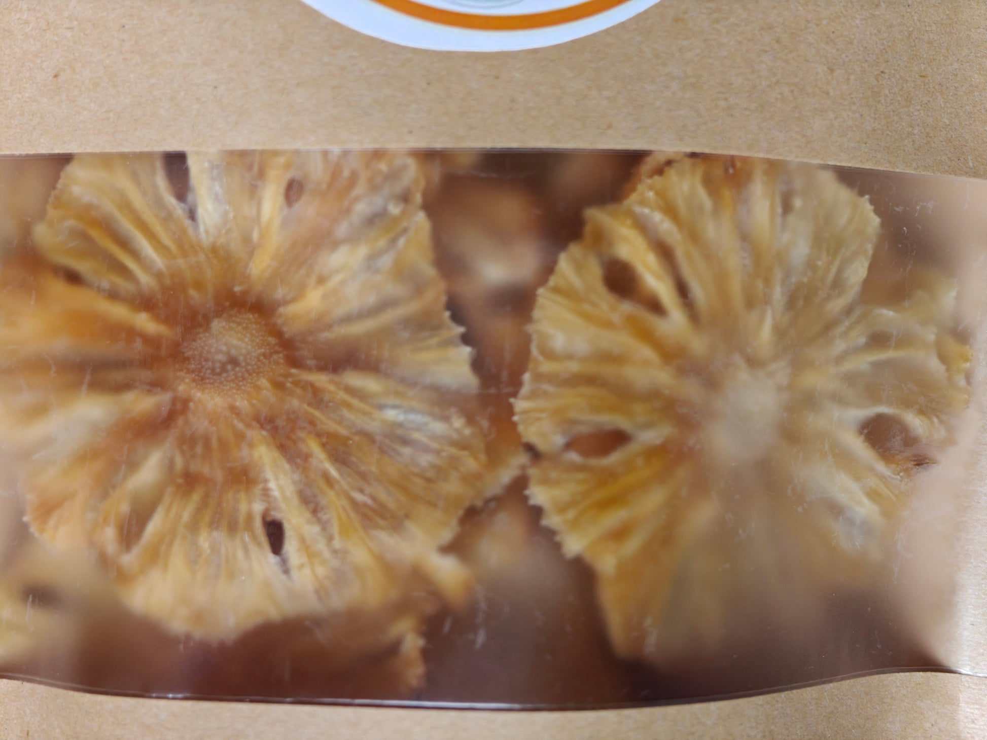 Dried pineapple slices in a clear packaging with a brown background
